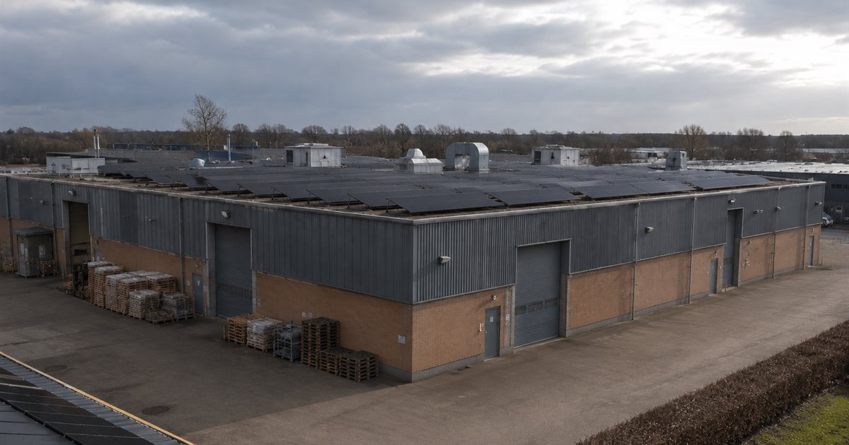 Produktionshal med solceller på det flade tag og paller i gården