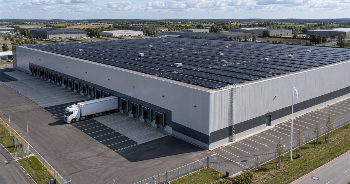 Stort logistikcenter med solceller over hele taget og lastbil ved rampen